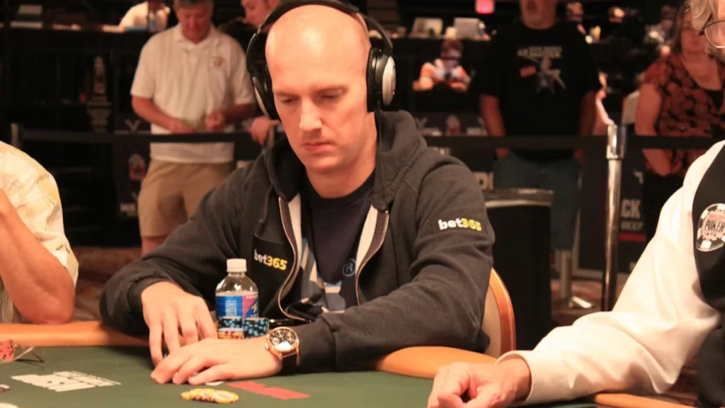 Jesper Hougaard spiller poker ved et turneringsbord med hovedtelefoner og chips foran sig.