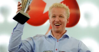Allan Bække løfter et trofæ og fejrer sin sejr i en stor pokerturnering.