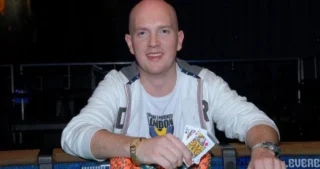 Jesper Hougaard sidder ved et pokerbord med chips og spillekort under en pokerturnering.