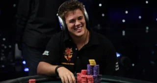 Pokerproffen Jonas Klausen smiler ved pokerbordet med høretelefoner og store stakke chips